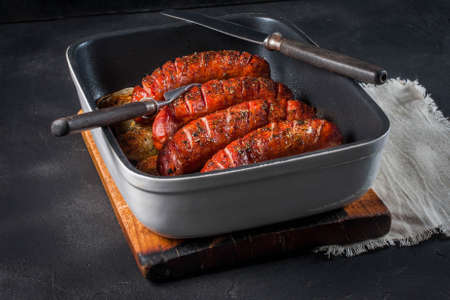 Sausages baked with onion rings in brytfance. with onion rings in brytfance.の写真素材