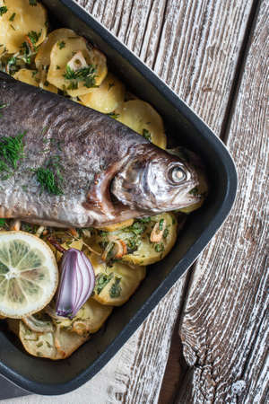 Baked trout with potatoes and onions, sprinkled with parsley.の写真素材