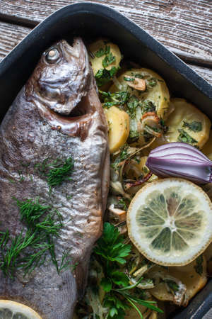 Baked trout with potatoes and onions, sprinkled with parsley.の写真素材