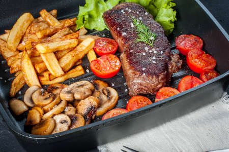 Fried steak with fries mushrooms and tomatoes.の写真素材