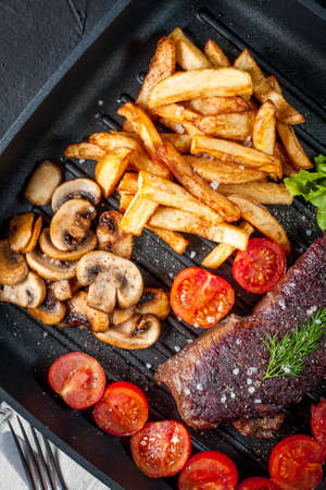 Fried steak with fries mushrooms and tomatoes.の写真素材