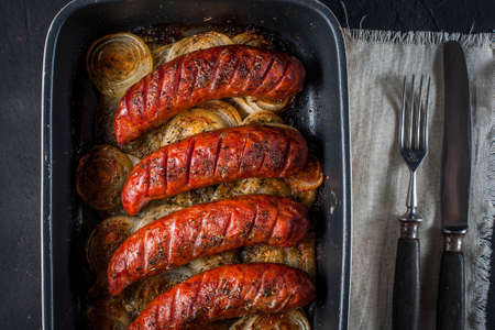 Sausages baked with onion rings in brytfanceの写真素材