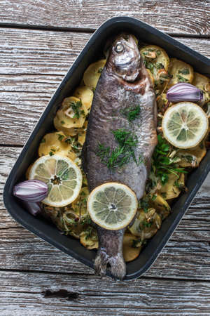 Baked trout with potatoes and onions, sprinkled with parsley.の写真素材