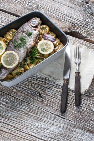 Baked trout with potatoes and onions, sprinkled with parsley.の写真素材