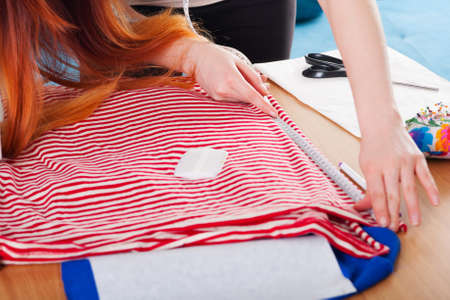 Woman measuring pattern on fabric with tailor meter