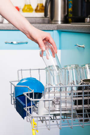 Woman empty out the dishwasher in kitchenの写真素材