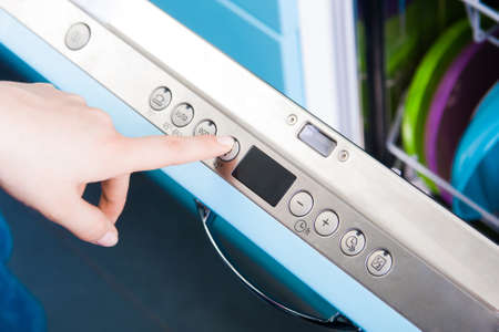 Woman set the dishwasher program in kitchen