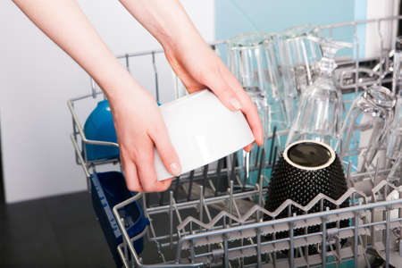 Woman empty out the dishwasher in kitchen