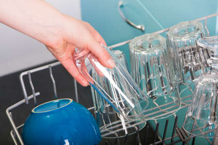 Woman empty out the dishwasher in kitchenの写真素材
