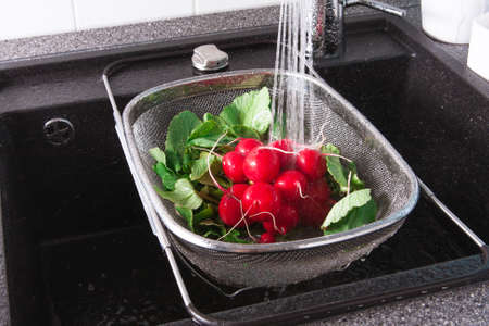Rinse fresh vegetables in the sink with waterの写真素材