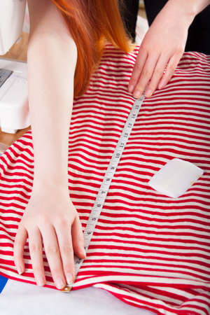 Woman measuring pattern on fabric with tailor meter