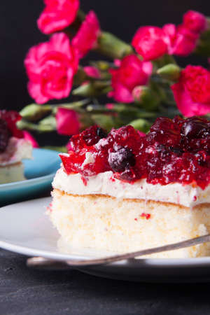 Piece of forest fruit cake with jelly and cream on a plateの写真素材