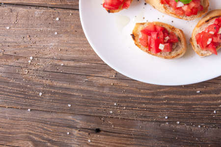 Plate of bruschetta with tomato, onion and basil on a wooden tableの写真素材