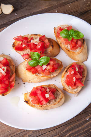 Plate of bruschetta with tomato, onion and basil on a wooden tableの写真素材