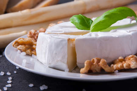 Blue cheese and camembert on plates with ciabatta, walnuts and asparagus, decorated with basilの写真素材