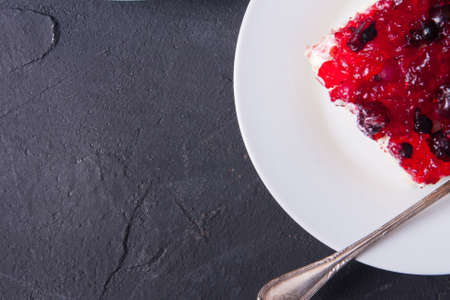 Piece of forest fruit cake with jelly and cream on a plateの写真素材