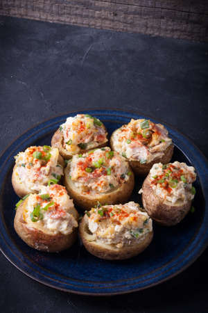 Baked stuffed potatoes with bacon, eggs and chives on a plateの写真素材
