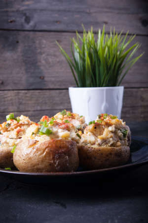 Baked stuffed potatoes with bacon, eggs and chives on a plateの写真素材