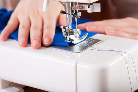 Young woman sewing fabric on sewing machineの写真素材