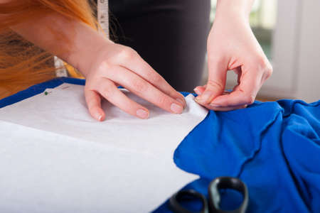 Woman measuring pattern on fabric with tailor meter