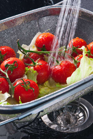 Rinse fresh vegetables in the sink with waterの写真素材