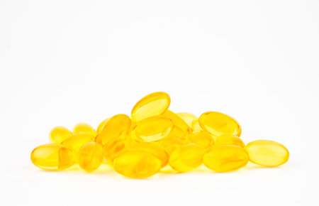 Heap of yellow oil soft gel capsules isolated on white backgroundの写真素材
