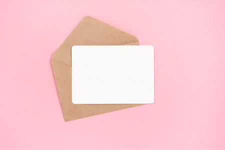 Empty greeting card with envelope on pale pink background, top view with copy spaceの写真素材