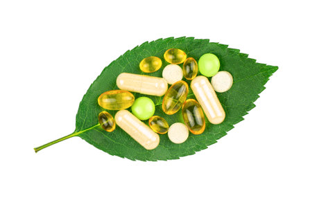 Variety of dietary pills on fresh green leaf supplement isolated on white background, top view. alternative medicine conceptの写真素材