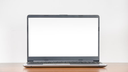 Laptop with blank display on empty wooden table against white wall background, copy space, modern minimalistic interiorの写真素材