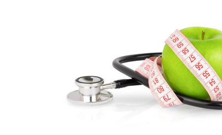 Green apple with measuring tape and stethoscope isolated on white background with copy space. Healthy eating and dieting conceptの写真素材