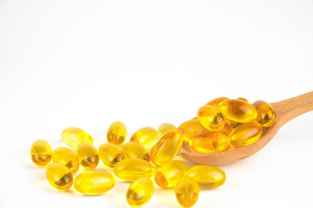 Omega 3 capsules in wooden spoon and around it on white backgroundの写真素材