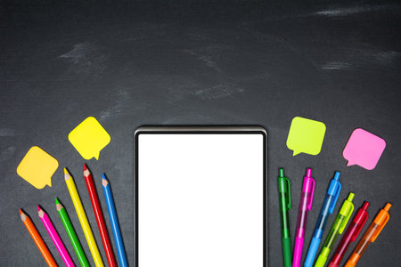 Digital tablet with blank screen and school supplies on blackboard background, top view, copy space. e-learning conceptの写真素材