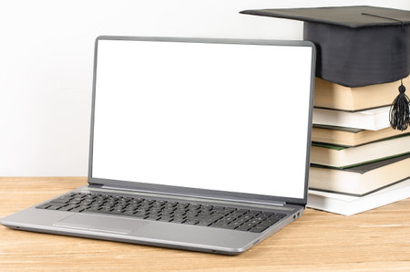 Laptop with blank display near the stack of book with graduation hat. E-learning and online graduation conceptの写真素材