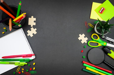 Vibrant school supplies, notepad and plant on black background, frame composition with copy spaceの写真素材