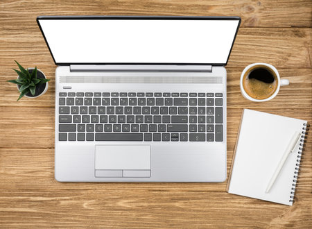 Top view wooden desk with blank display laptop, notepad, coffee and green plant. Modern workplaceの写真素材