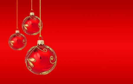 Hanging Christmas ornaments on red background with copy spaceの写真素材