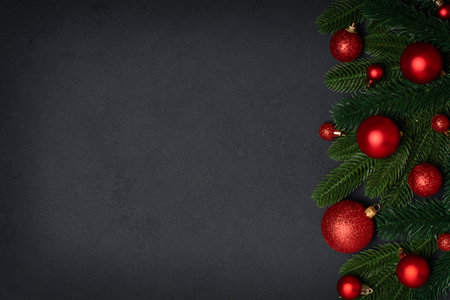 Fir tree branches with Christmas decorations on black background. Christmas background with copy space, border compositionの写真素材