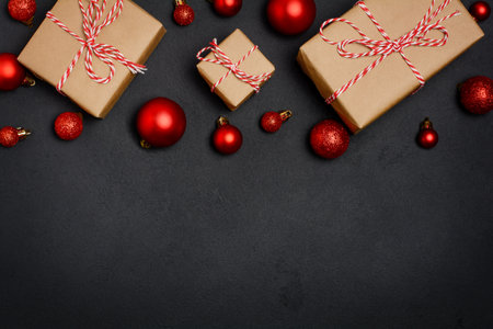 Christmas gift boxes and decorations on black background, top view with border compositionの写真素材