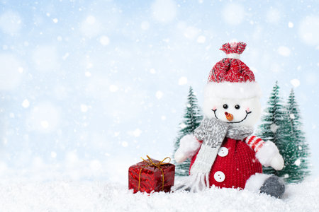 Snowman with gift box on snowy day, Christmas greeting card with copy spaceの写真素材