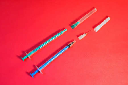 Medical syringes for dosing and injecting the drug under the skin. Lie on a red paper background, indicative. Treatment by vaccination against SARS-CoV-2. copyspace.の写真素材