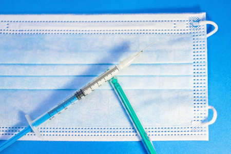 A blue mask with a blue background and a syringe for injection for healthcare workers and people at...