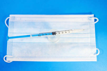 A blue mask with a blue background and a syringe for injection for healthcare workers and people at...
