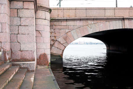 Lonely landscape views from a cold autumn bridge made of iron and stone to the freezing river of the coming winterの写真素材