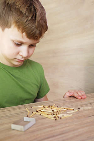 A child looks and plays with matches, a dangerous activity for a toddler at home.の写真素材