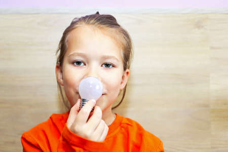 A girl demonstrates a light bulb as a symbol of light and new technologies in the modern world