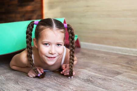 girl child in sportswear on a rubber gymnastic mat shows a healthy lifestyle, always having fun and in good shapeの写真素材