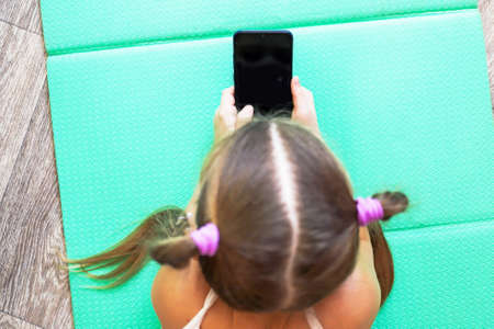 girl child with pigtails talking on the phone, getting homework on a cellular connection, during isolation and a pandemic, a convenient means of communicationの写真素材