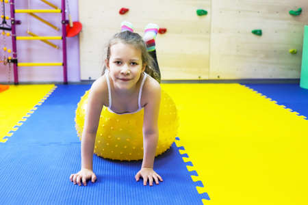 an autistic girl is being treated in a children's center by psychologist doctor, holding a yellow spiked big ballの写真素材