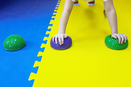 a little girl works on herself and stands in rack on spiked balls and does push-ups in a children's centerの写真素材