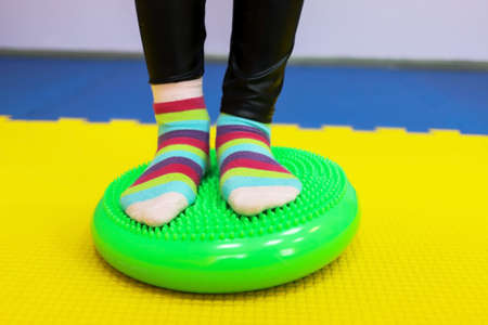 a little girl walks with her feet on a studded ball in children's center as if on a trackの写真素材